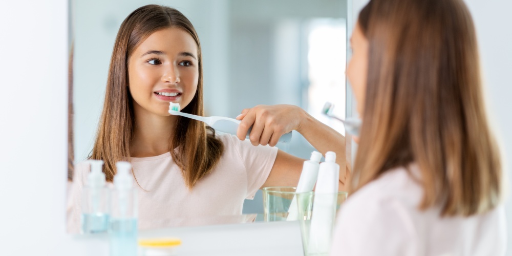 dziewczynka szczotkuje zęby szczoteczką elektryczną