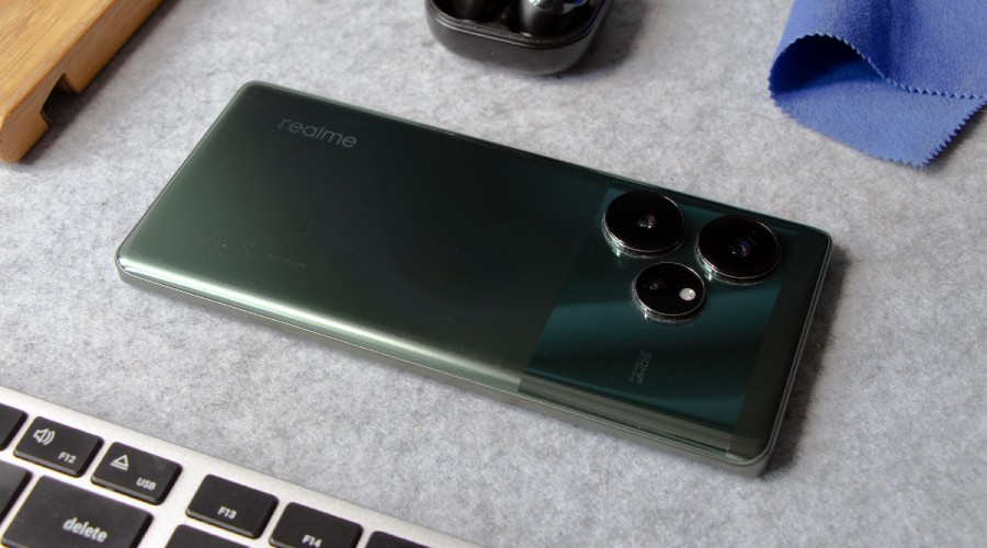 zielony realme GT 6 leżący ekranem do dołu na szarej macie